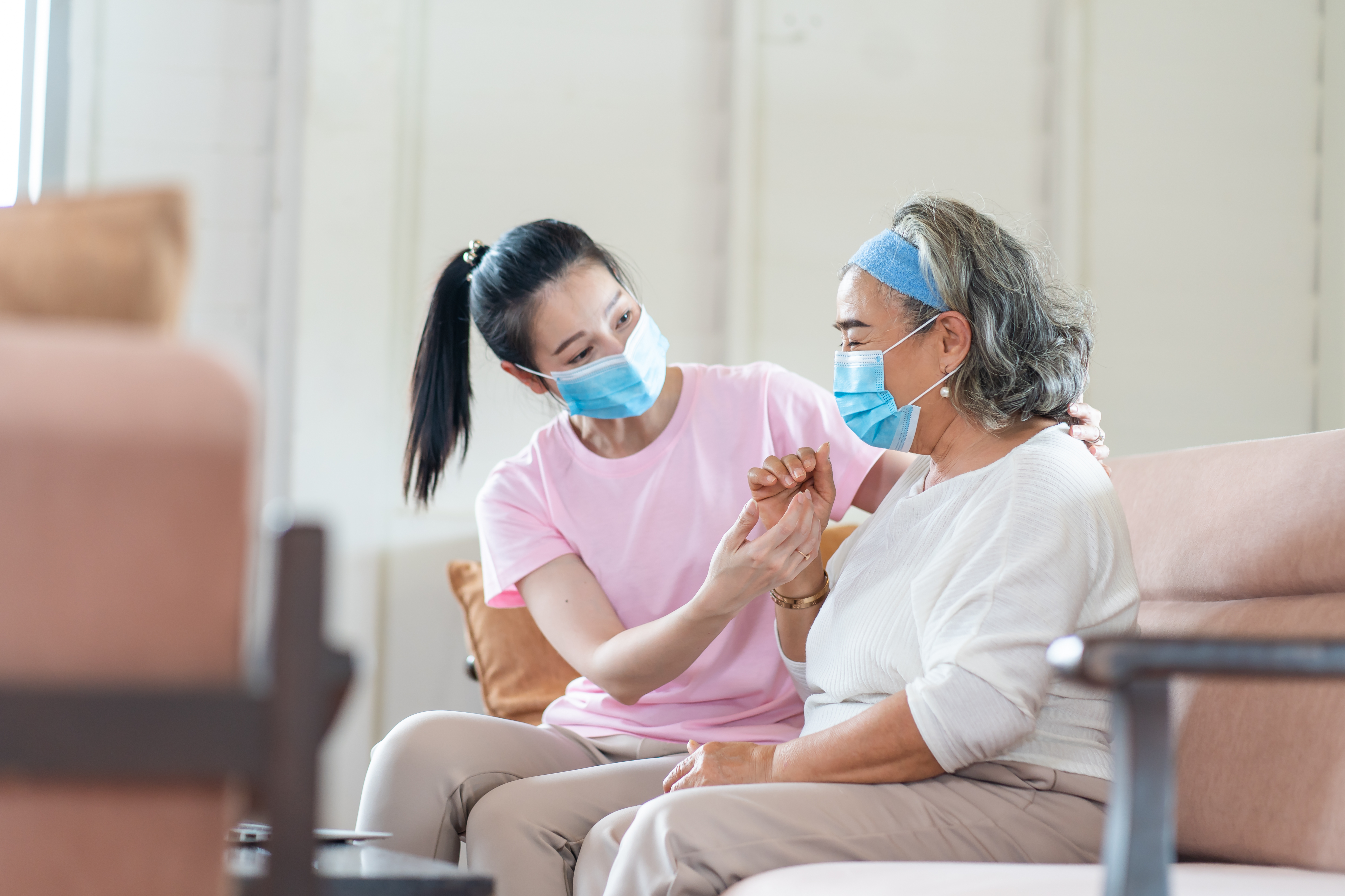 Photograph of a caregiver and client, both sitting and wearing medical masks